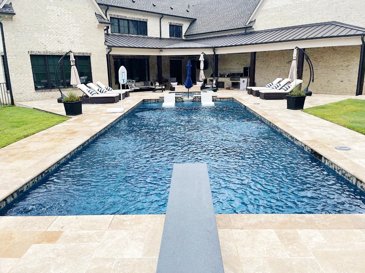 Modern rectangle pool with dark blue liner surrounded by natural stone tile.