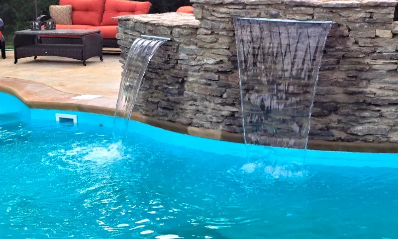 A closeup of swimming pool natural stone wall and waterfall.