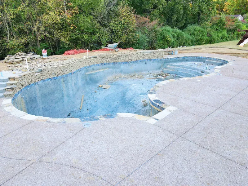 Adding a natural stone wall during swimming pool construction.