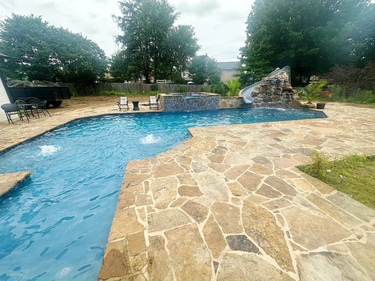 Custom shape pool with large natural stone decking.