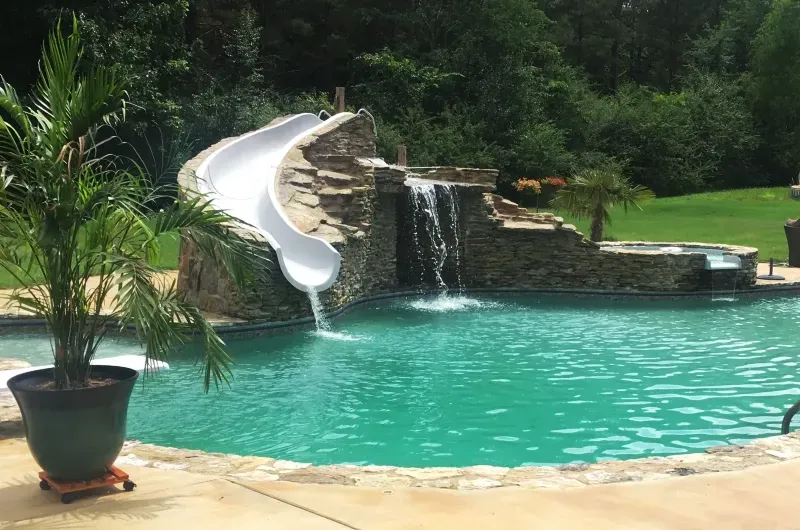 Water slide with natural stone swimming pool design.