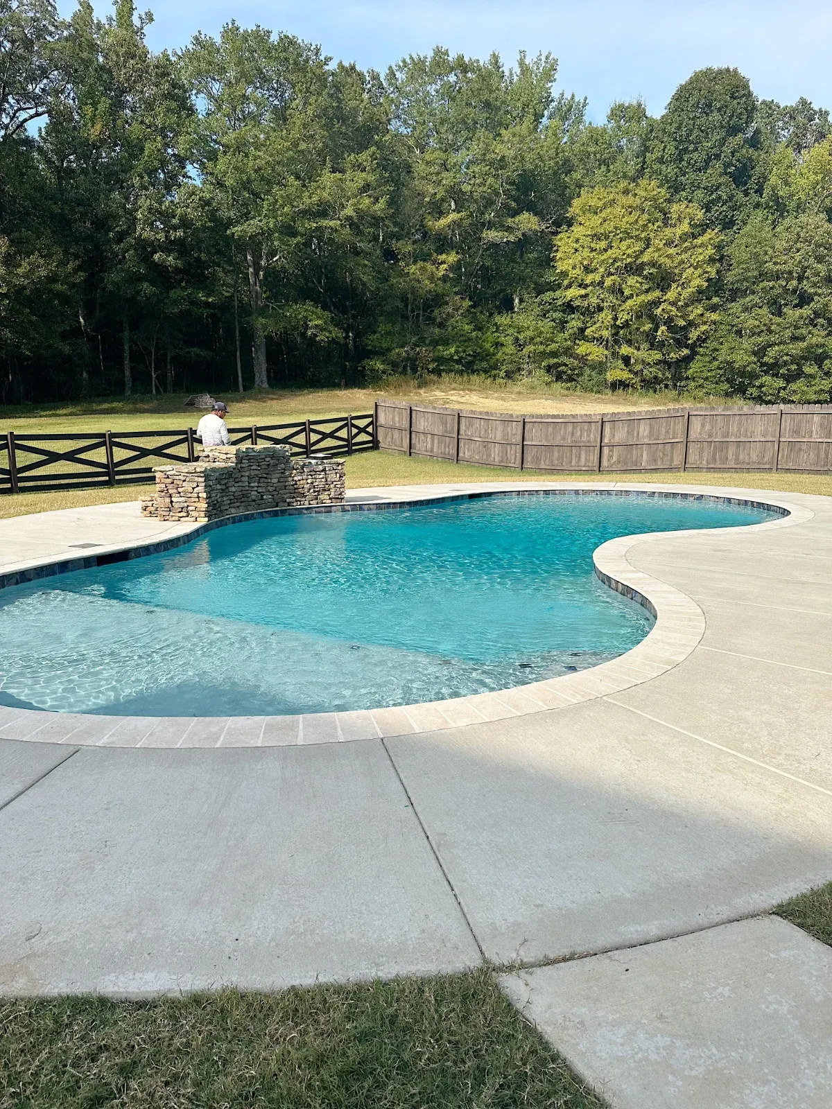 Lagoon style pool with concrete deck and tile edging.