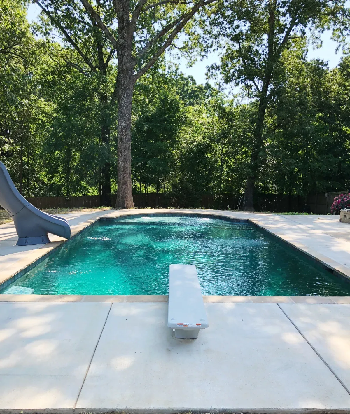 A classic rectangle pool design with water slide and diving board.